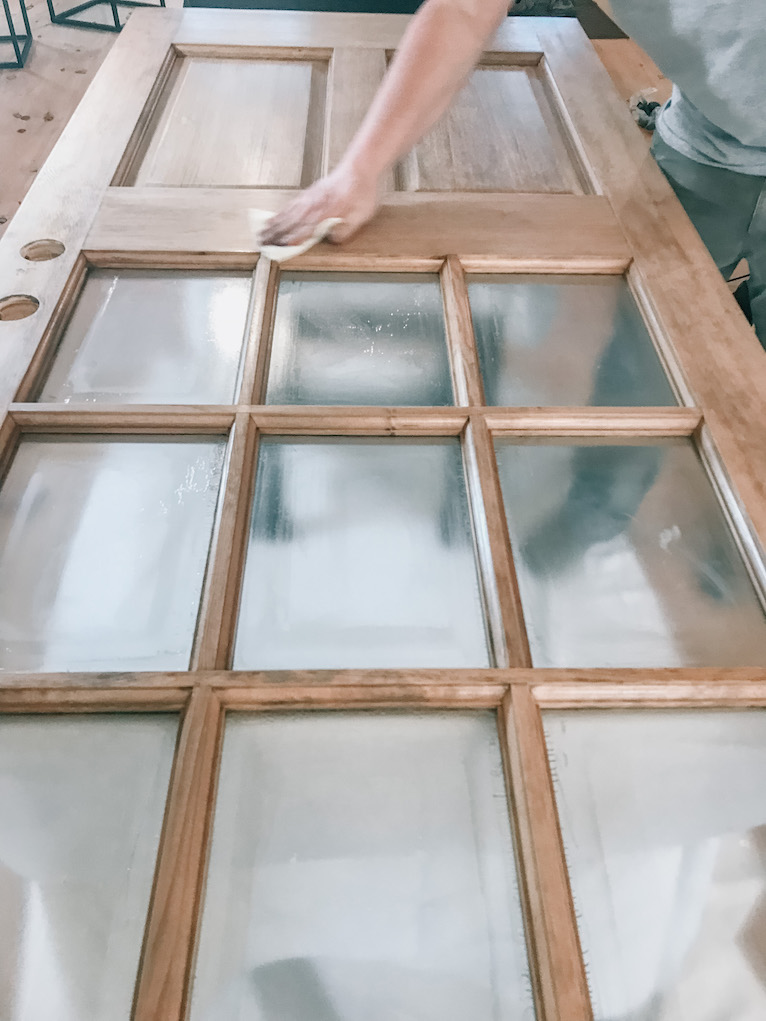 hand wiping a door with tack cloth to remove dust