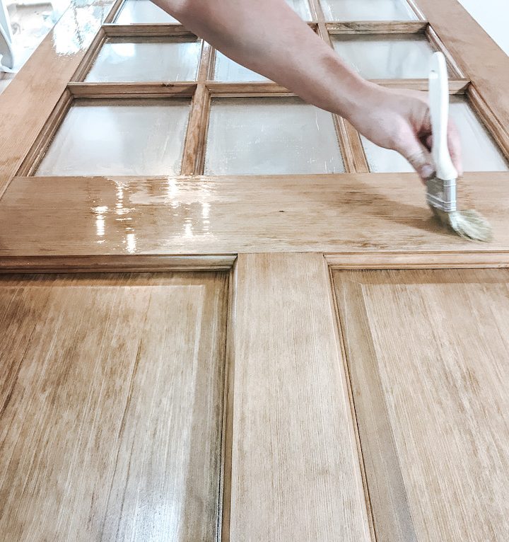 close up of hand using brush to apply sealer on wood door