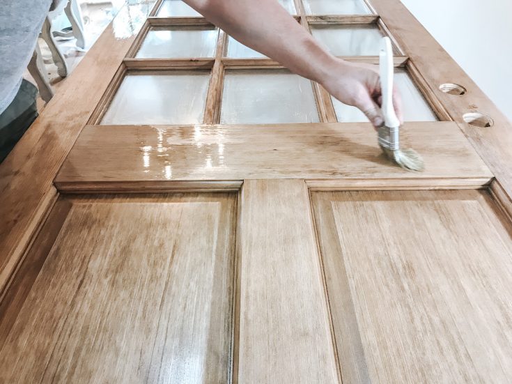 close up of hand using brush to apply sealer on wood door