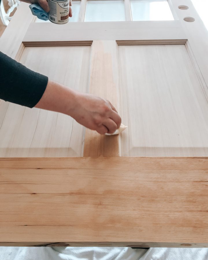 hand pre-staining bottom of bare wood door